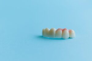 Artificial teeth on a blue background, dental crowns. Concept of dental implantation and restoration