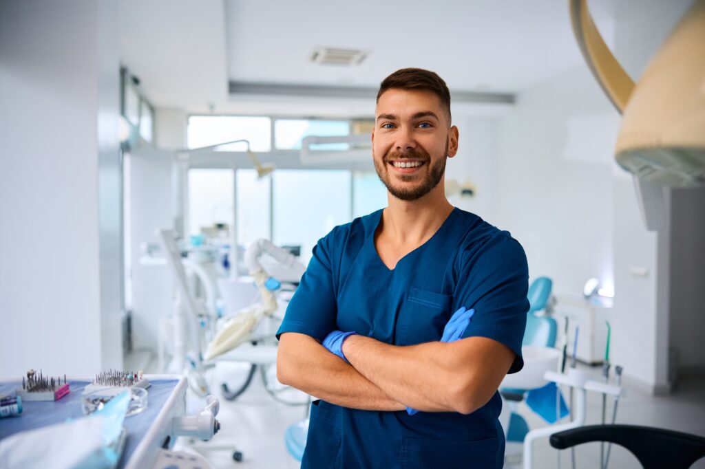 confident stomatologist standing with arms crossed at dentist s office an looking at camera 