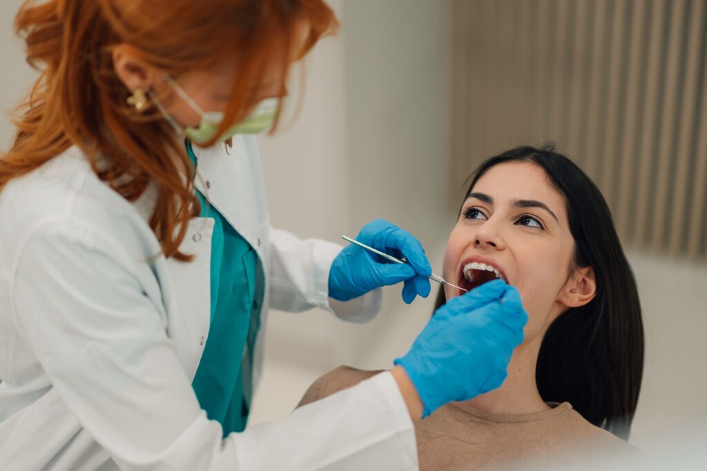 Dentist examining patient's teeth with dental tools in clinic