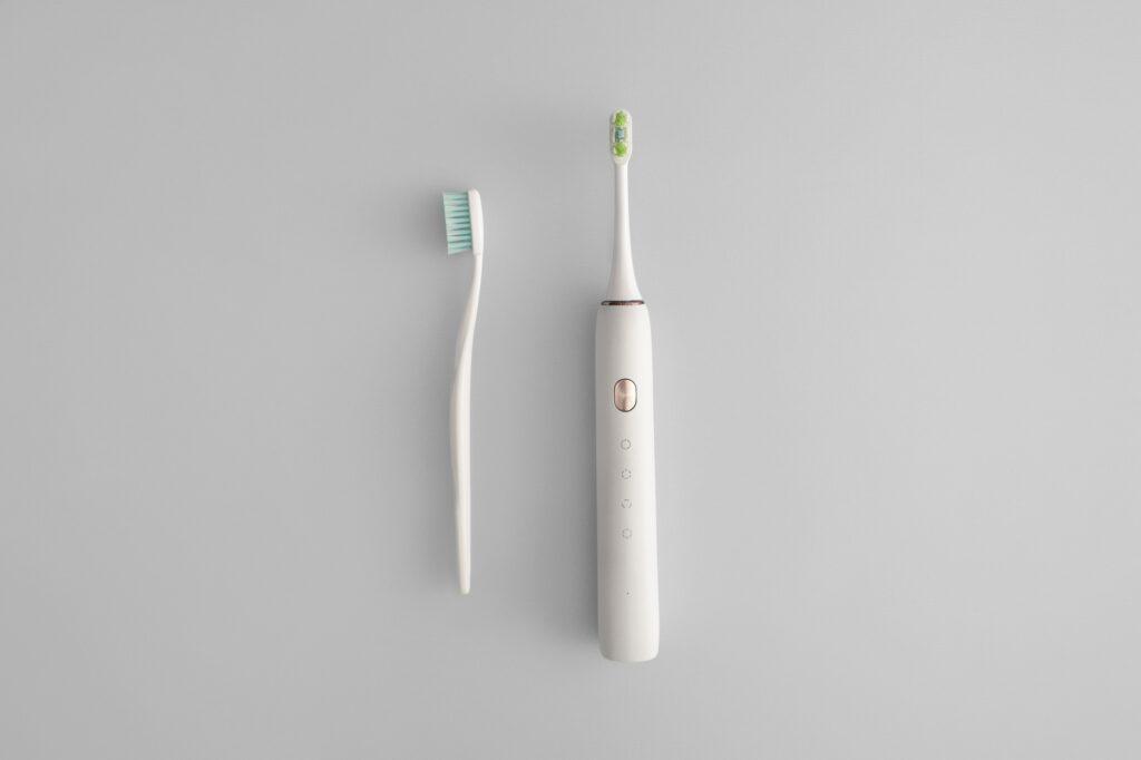 Manual and electric toothbrushes on grey background