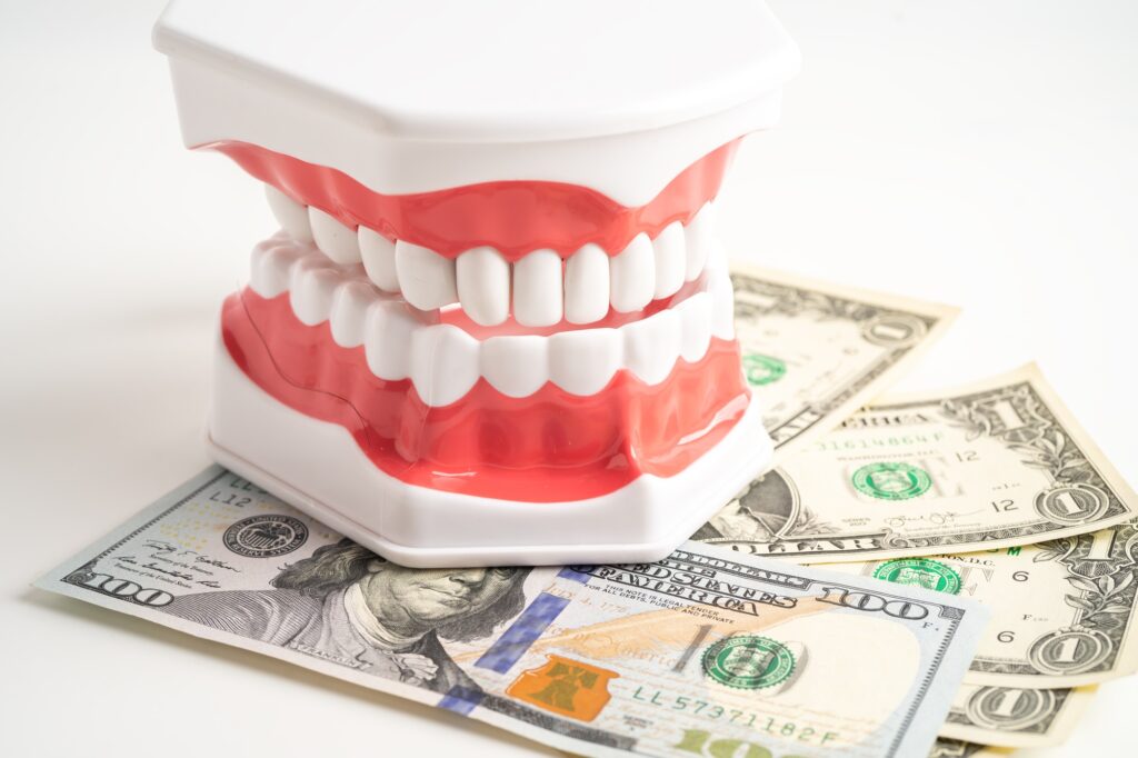 Treatment dental care cost, dental expense or fee, US dollar banknote money with teeth model.