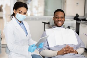 dental insurance concept black dentist woman and male patient posing in clinic