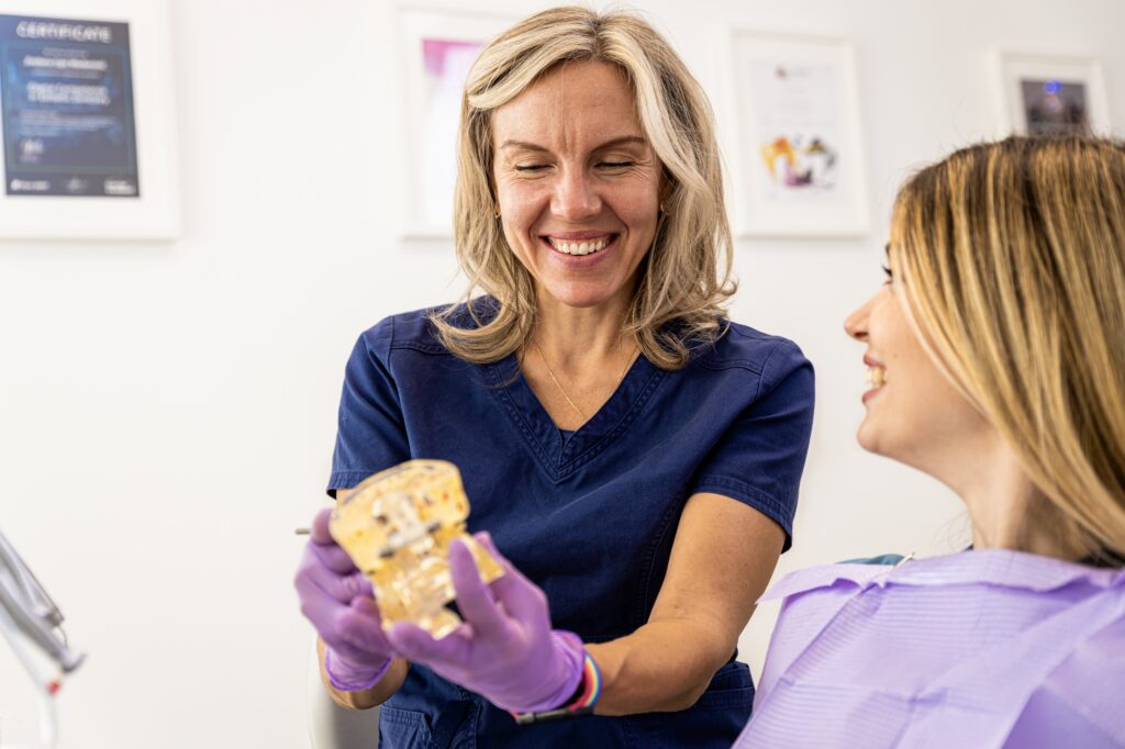 Female dentist takling with patient showing theet implant in dental clinic.