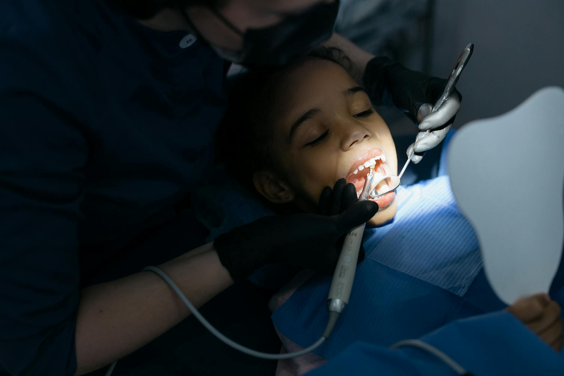 pediatric dentist examining child's teeth in modern dental office