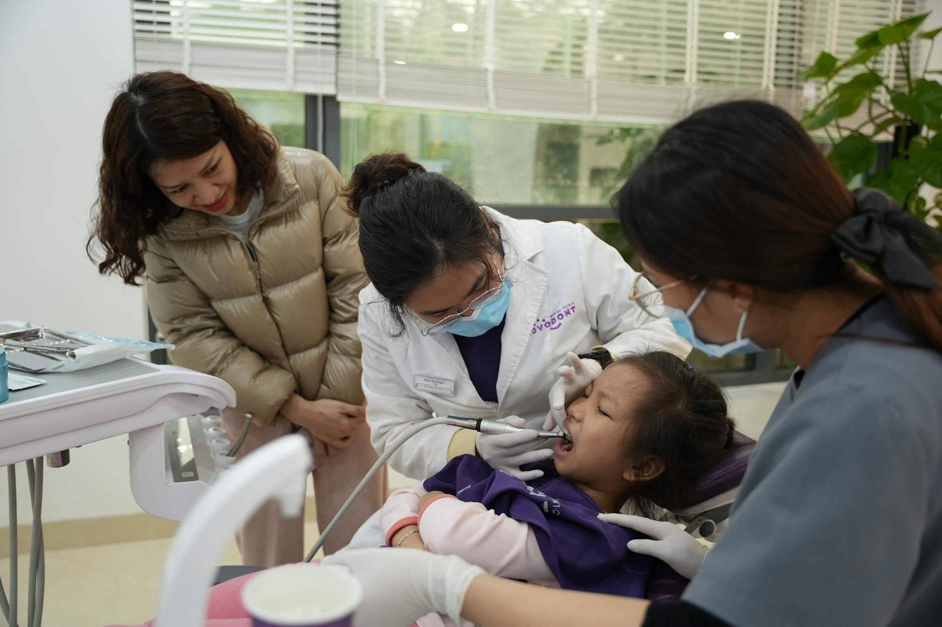 dentist examining child patient with parent watching