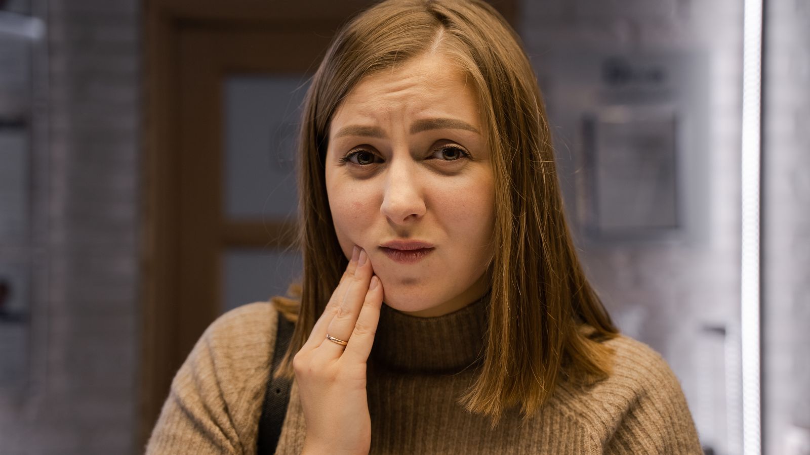 Person holding their cheek with tooth discomfort