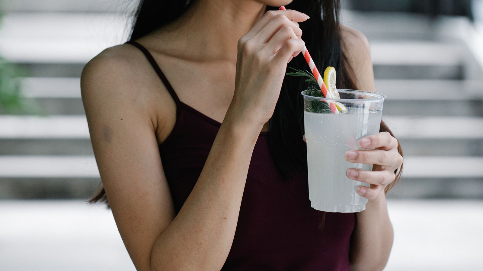 Person drinking a cold iced drink through a straw