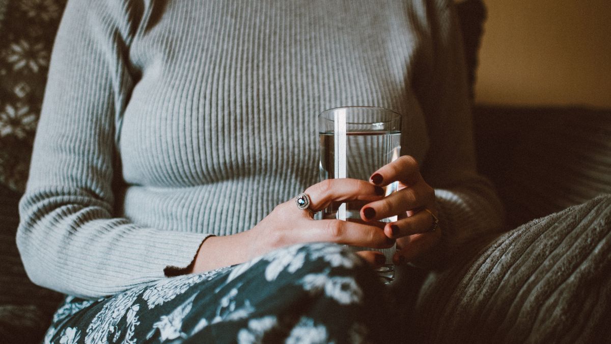 Person holding a glass of water while sitting at home