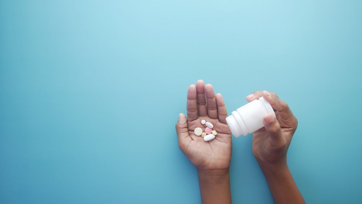 Hands tipping tablets out of a medication bottle
