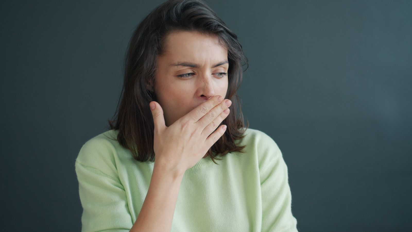Person covering their mouth with one hand