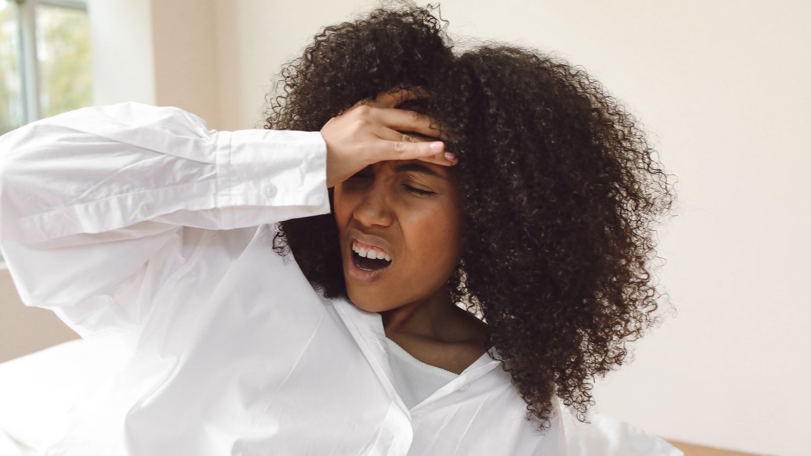 Person waking with a headache, hand pressed to their forehead