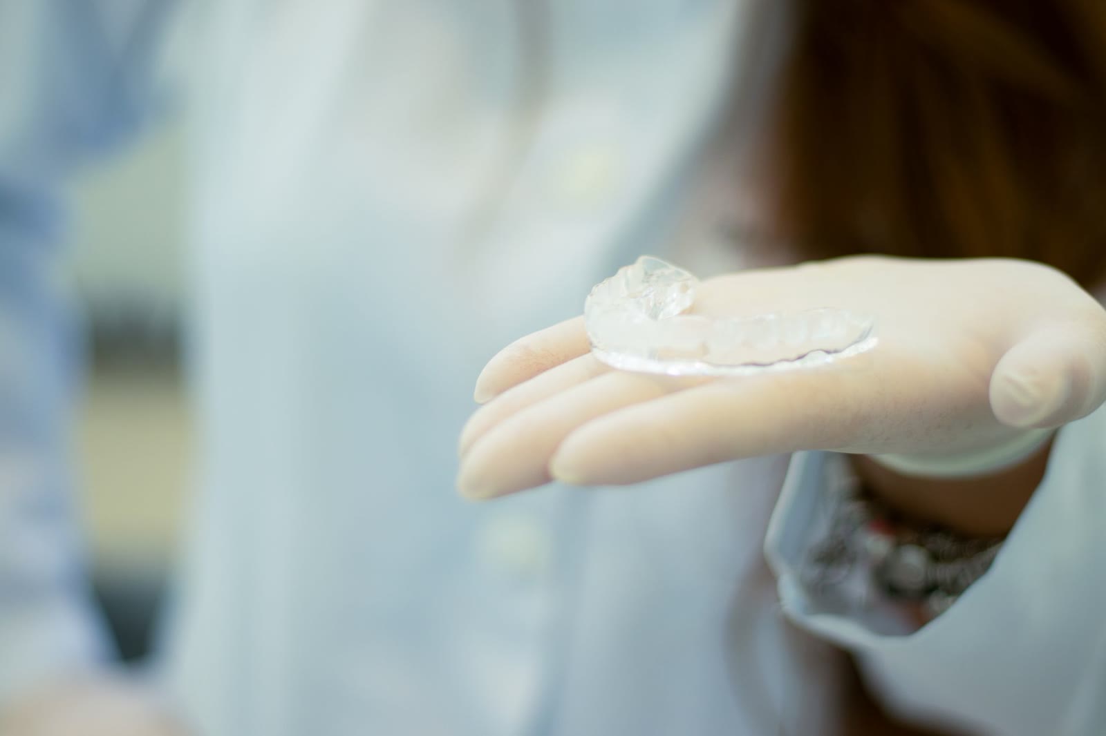 Gloved hand holding a clear removable dental mouthguard