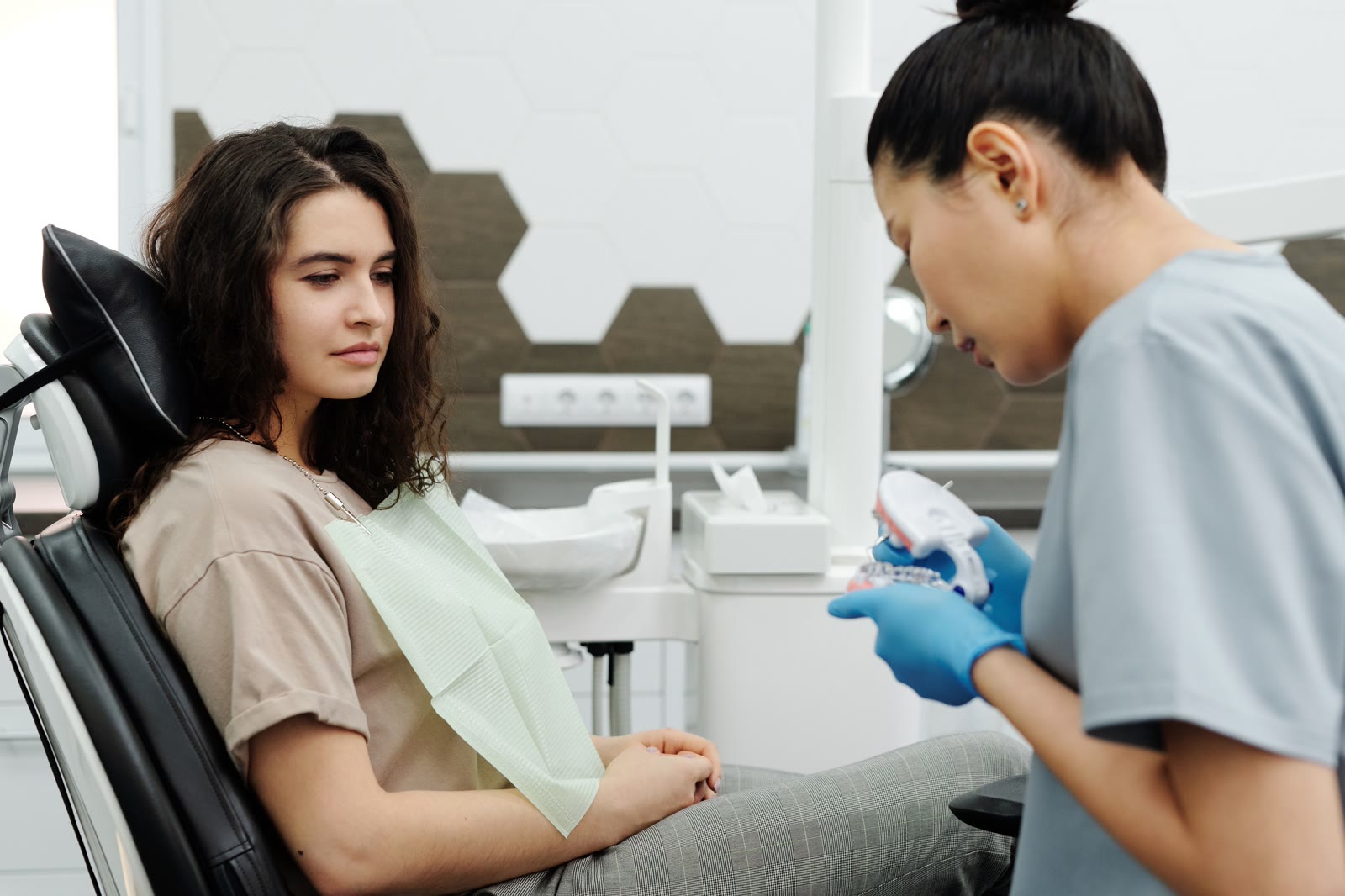 Dental professional holding a model of teeth beside a seated patient