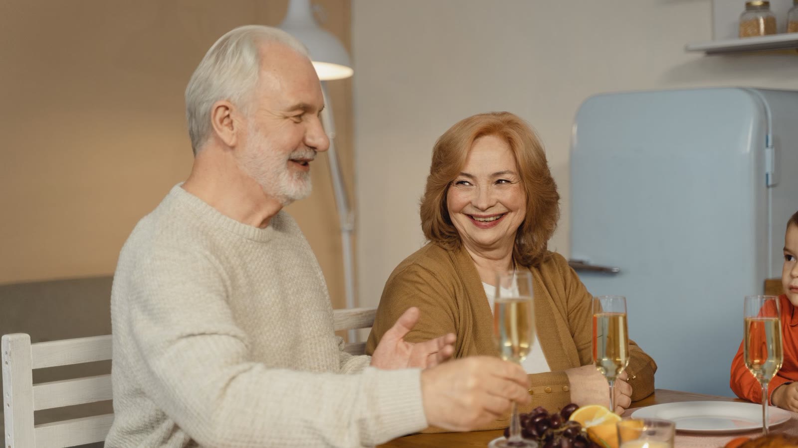 Older couple smiling together over a shared meal at a dinner table