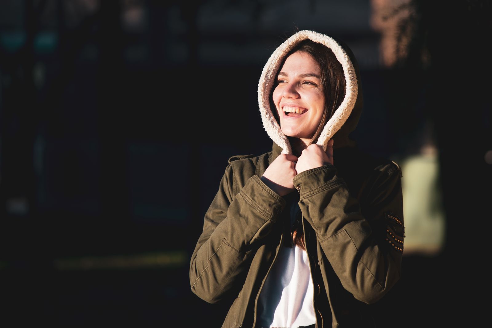 A cheerful woman in warm clothing enjoying a sunny day