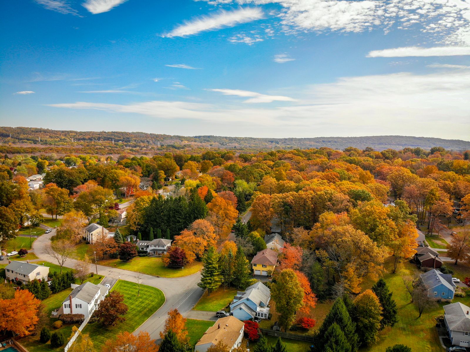 A stunning aerial view of a vibrant countryside with autumn foliage and clear blue skies