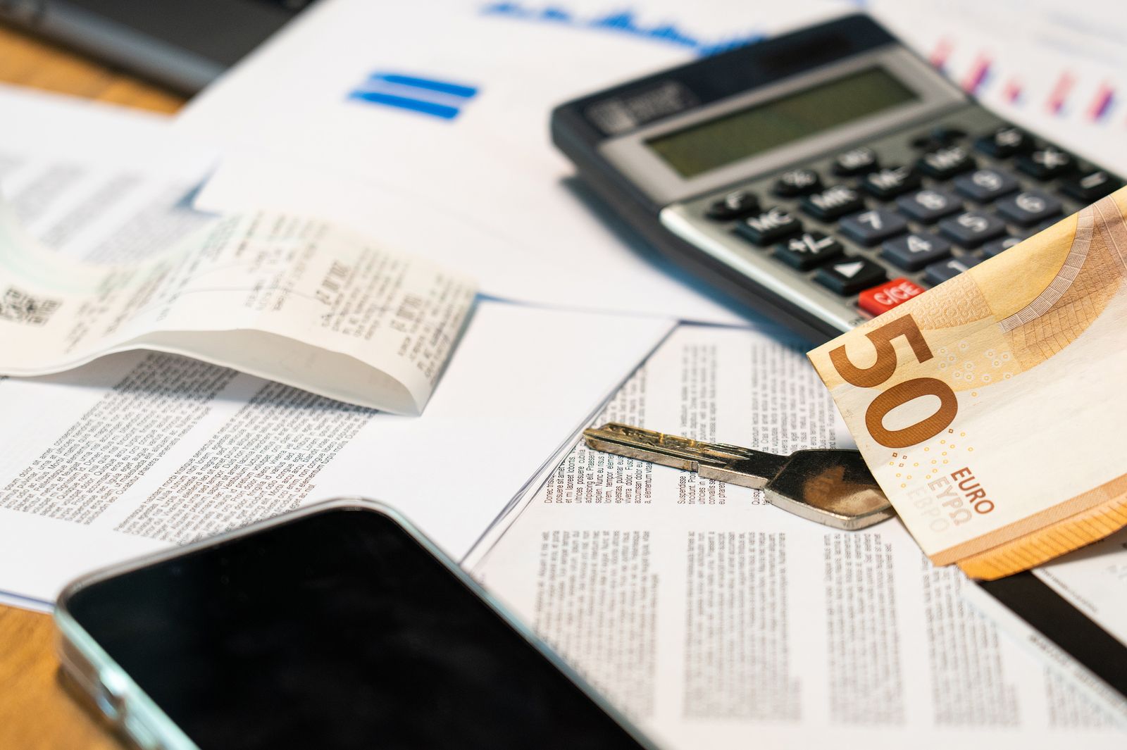 Flat lay of financial documents, euro note, calculator, smartphone, and key for budget management