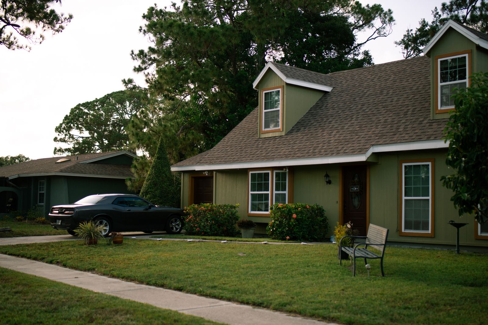 A beautiful suburban home with a well-maintained green lawn and parked car, highlighting residential comfort