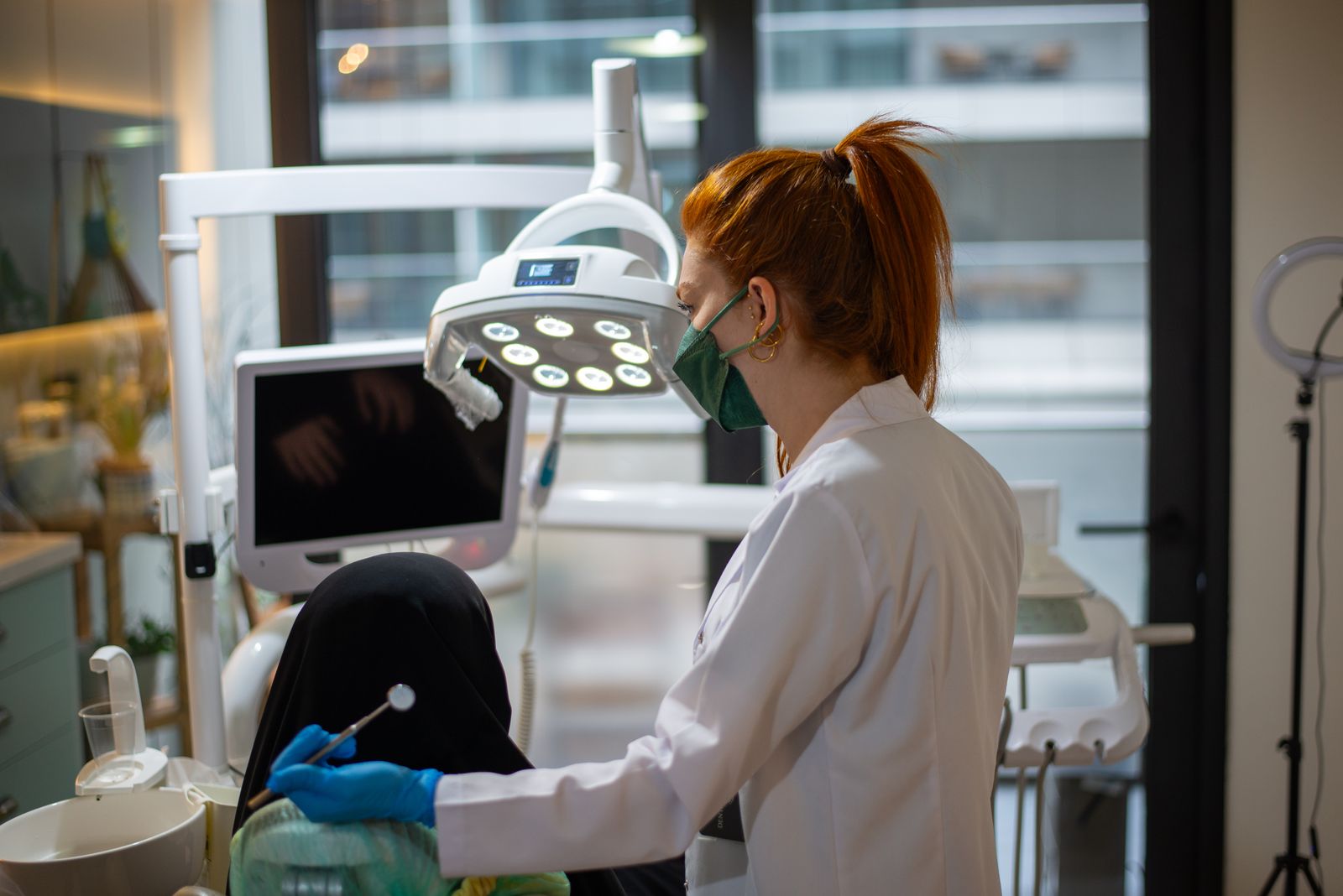 A dentist wearing a mask attends to a patient in a modern dental clinic with advanced equipment
