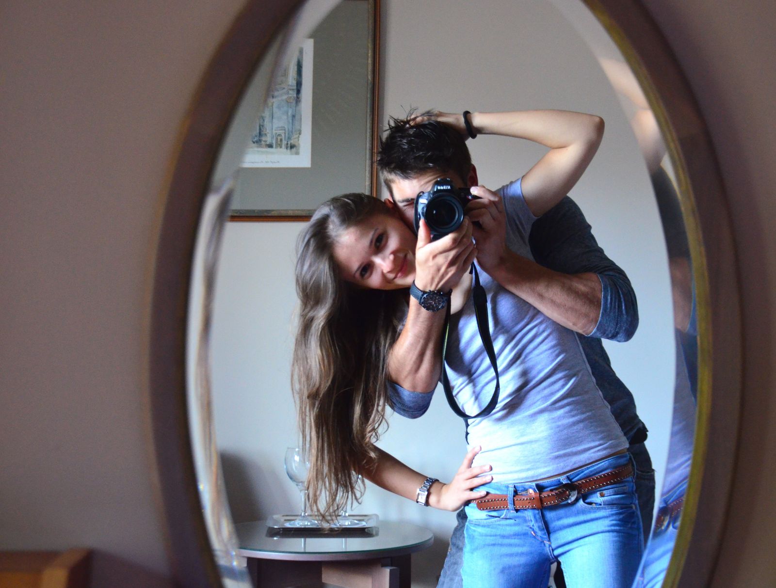 Smiling couple capturing a joyful moment with a mirror selfie indoors