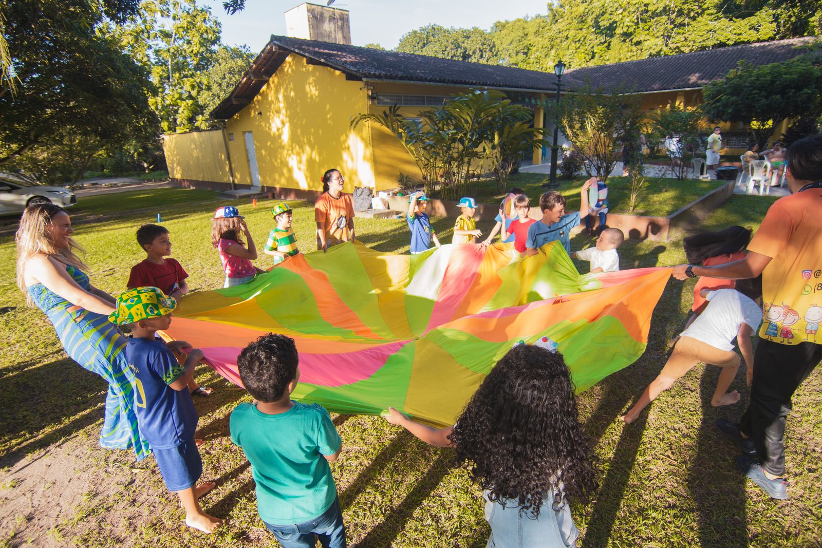 A lively group of children joyfully playing with a colorful parachute at an outdoor summer gathering