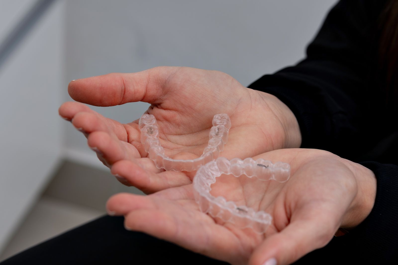 Hands holding clear dental aligners in a modern dental office in Belo Horizonte