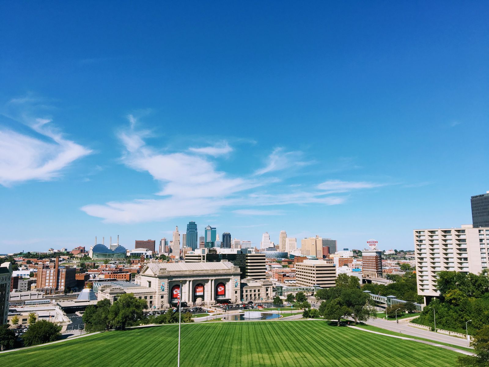 Wide-angle shot of Kansas City's skyline with clear blue skies and vibrant green foreground