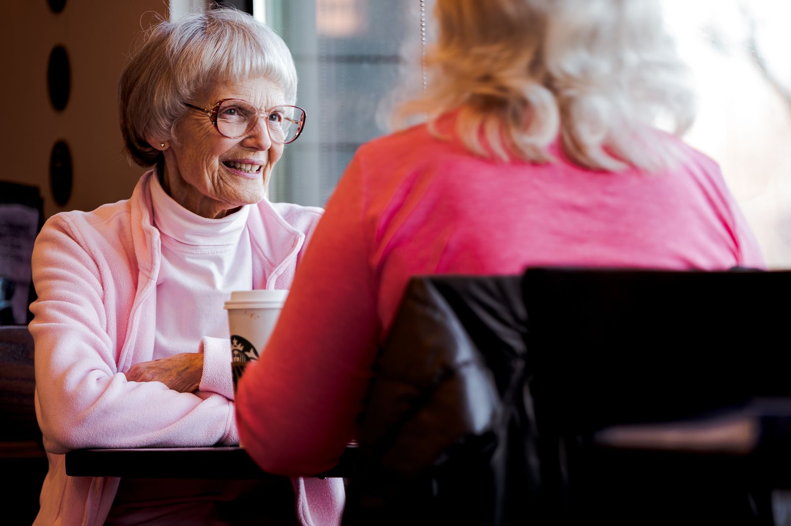 Senior women sharing a joyful conversation over coffee in a cozy indoor setting