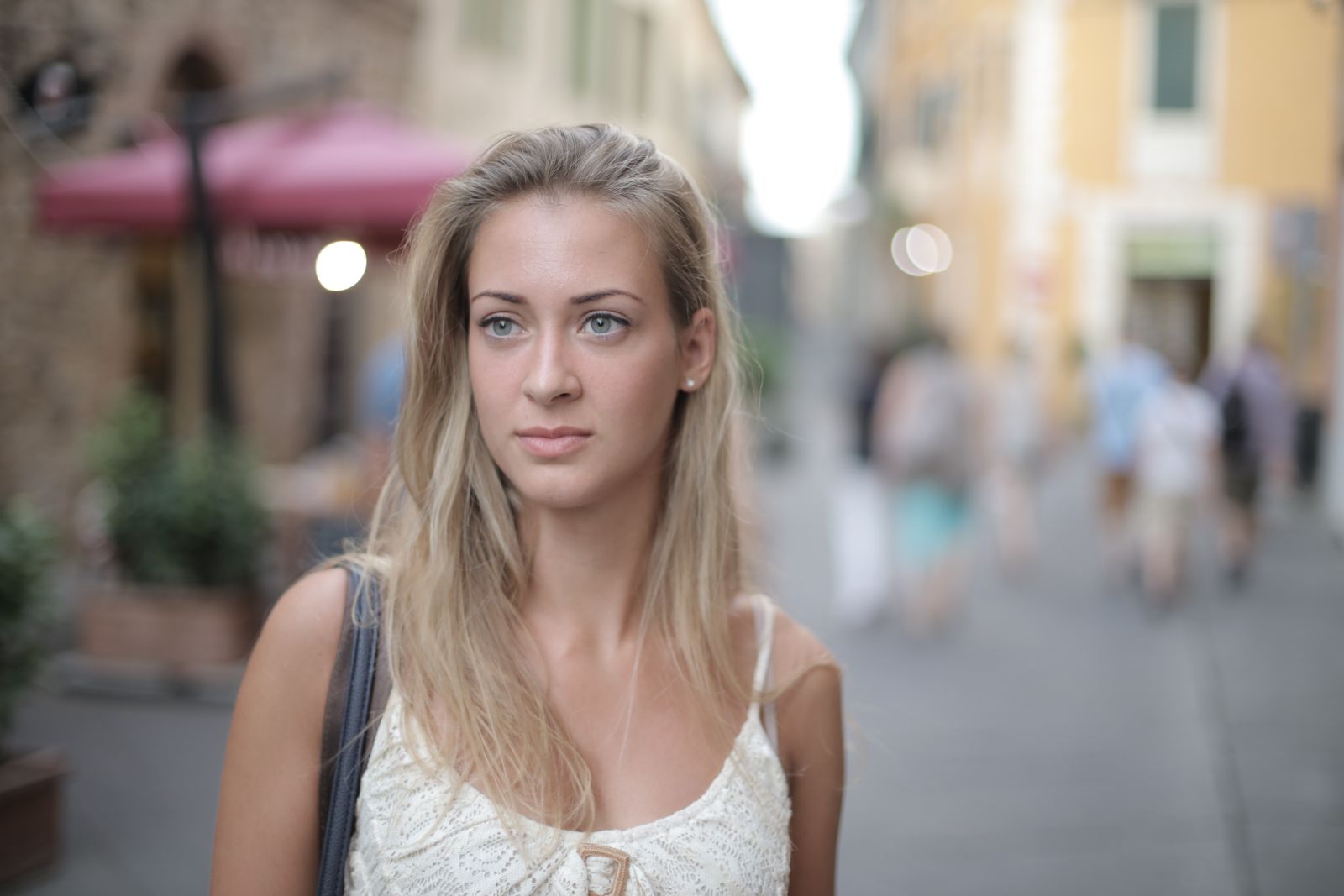 Elegant portrait of a woman with blonde hair, standing in a lively street setting