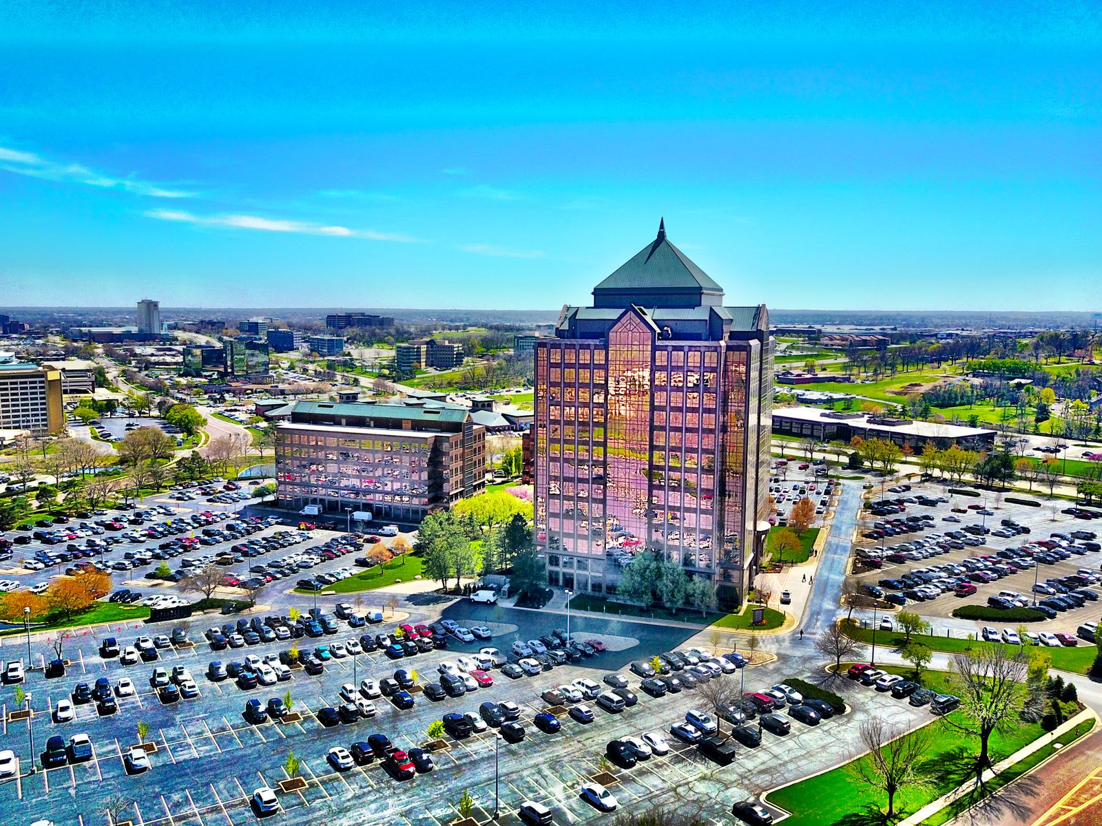 Bird's-eye view of a modern skyscraper and parking lot in Overland Park, KS, under a clear blue sky