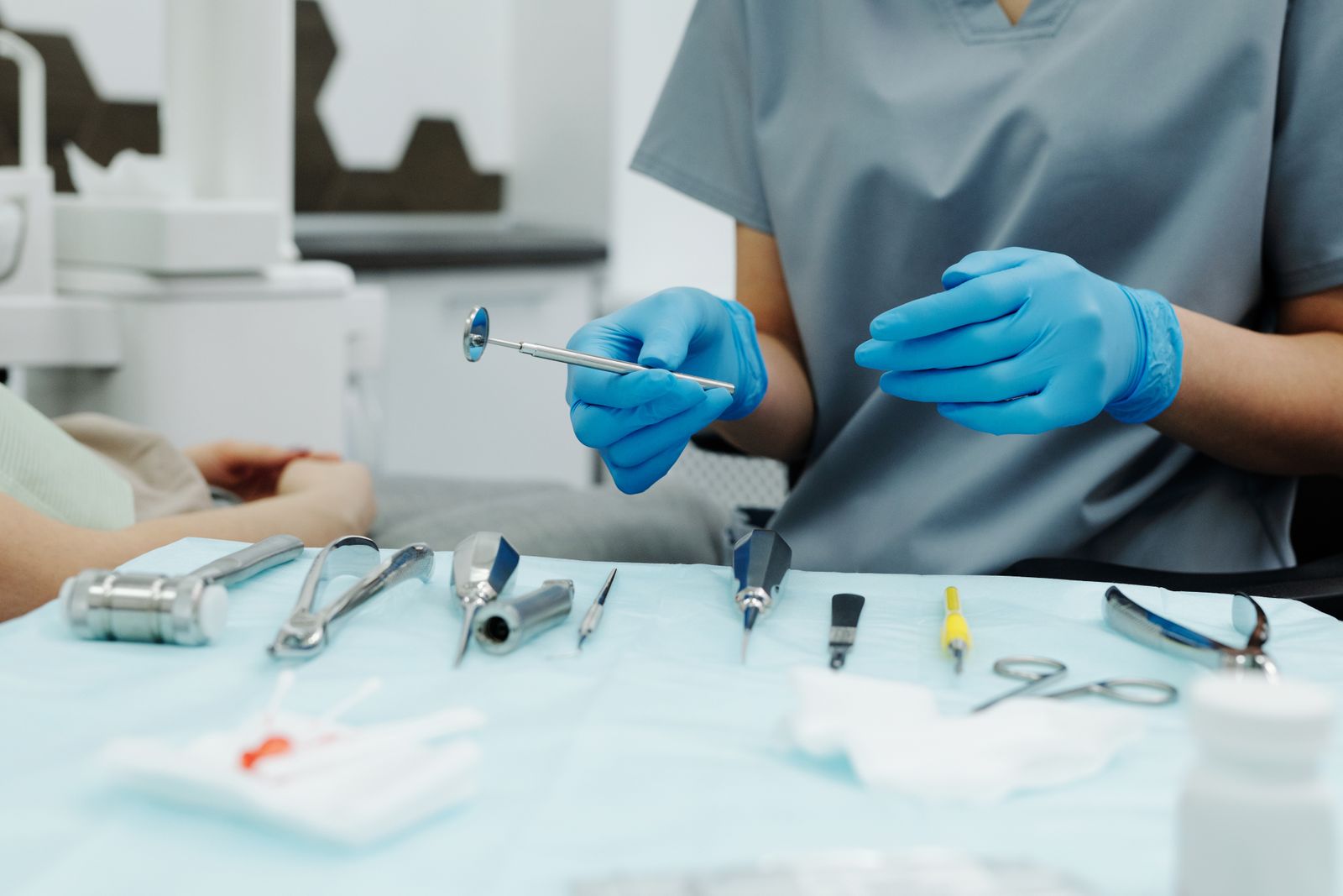 Dentist with gloves organizing instruments in a clinic setting, ready for a dental procedure