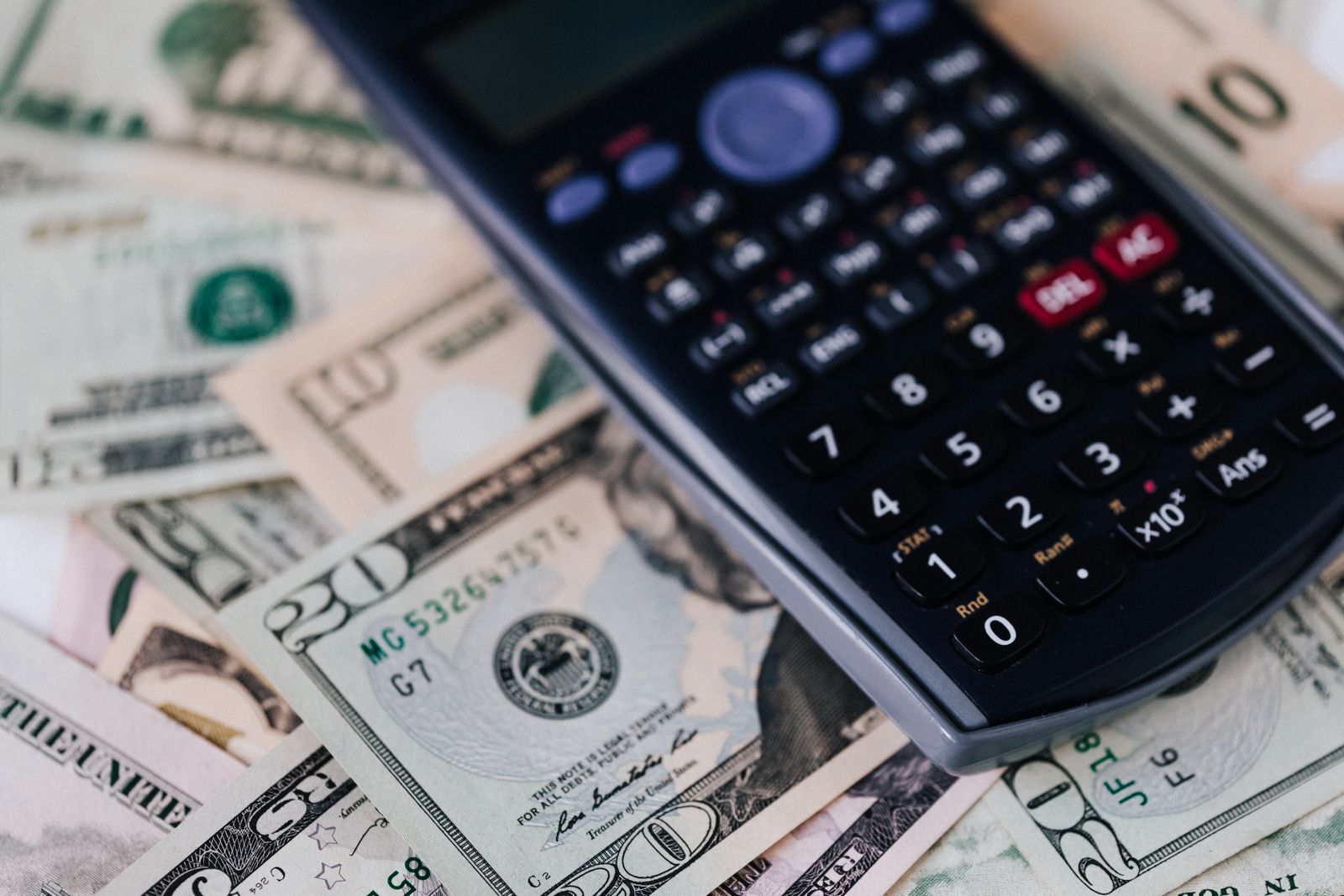 From above of electronic calculator placed over American cash paper money for budget planning and income and expenses calculation