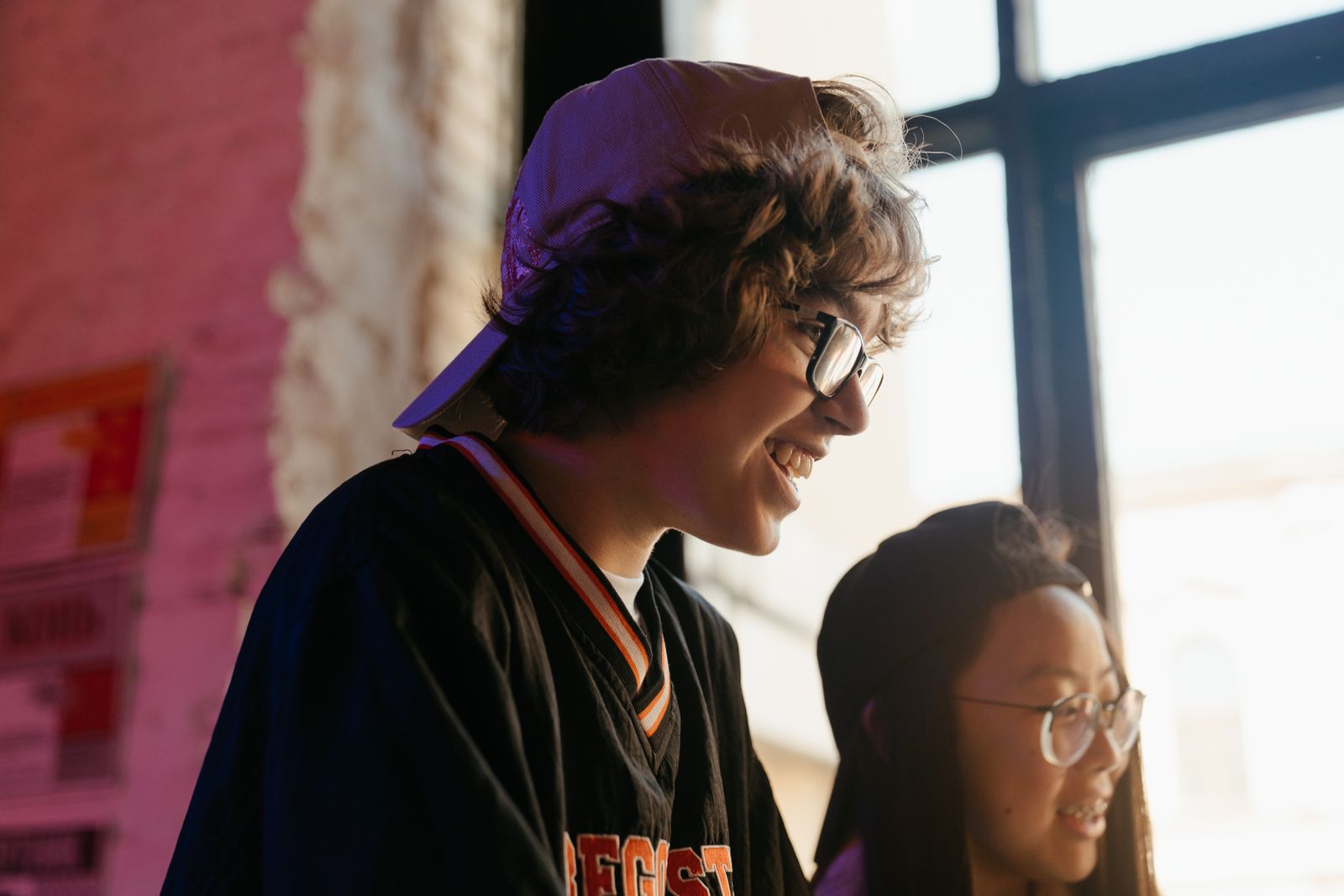 A group of diverse teenagers happily spending time together indoors by a window