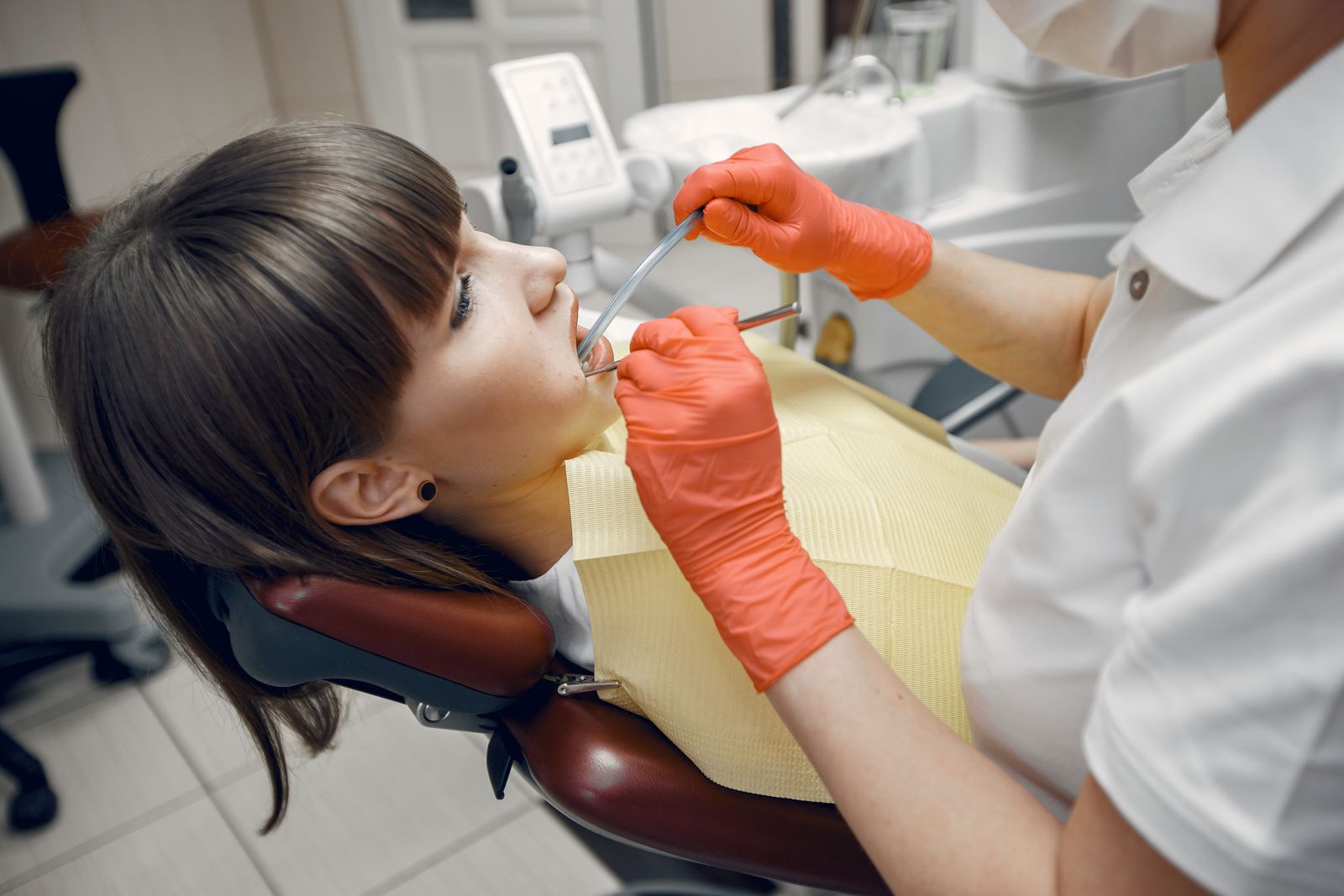 Dentist performing a checkup on a female patient using dental instruments and latex gloves