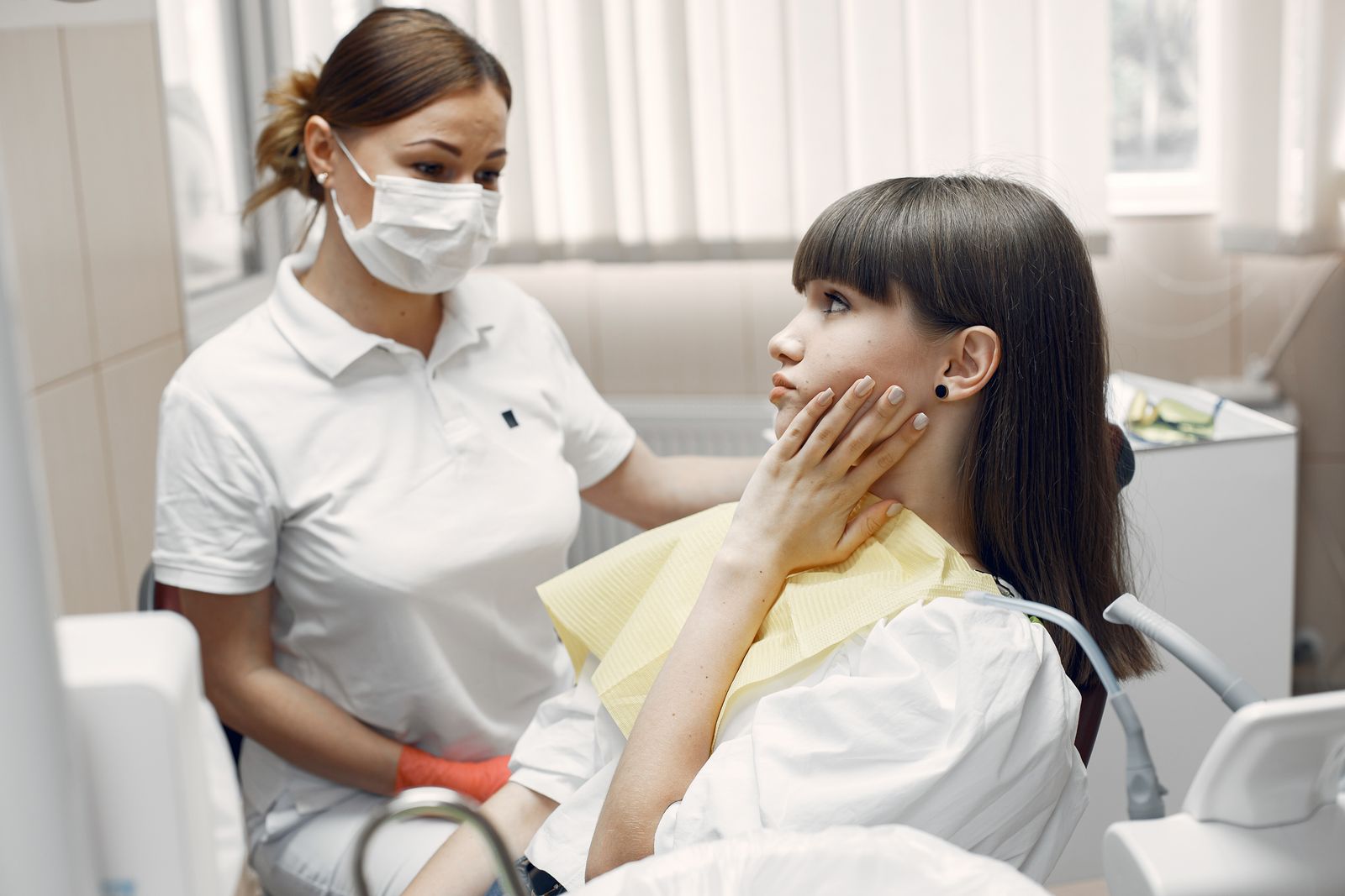 A dentist examining a young woman with toothache in a dental clinic