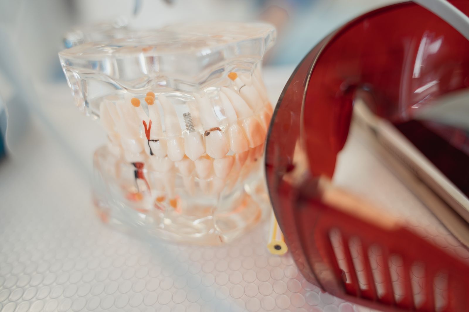 A dental model and red protective glasses on a textured surface, highlighting dental health tools