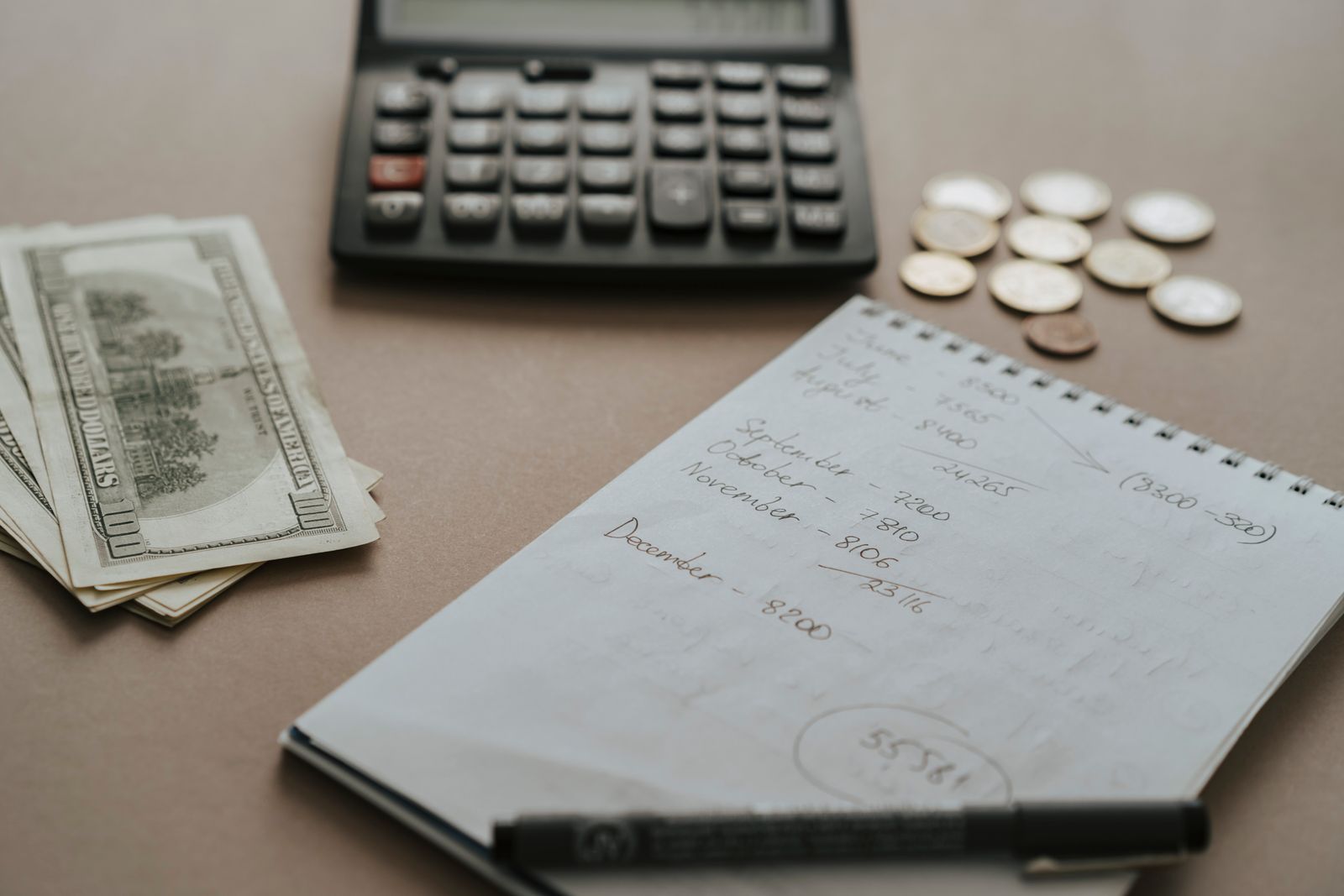 Desk setup showing calculator, cash, coins, and financial notes for budgeting