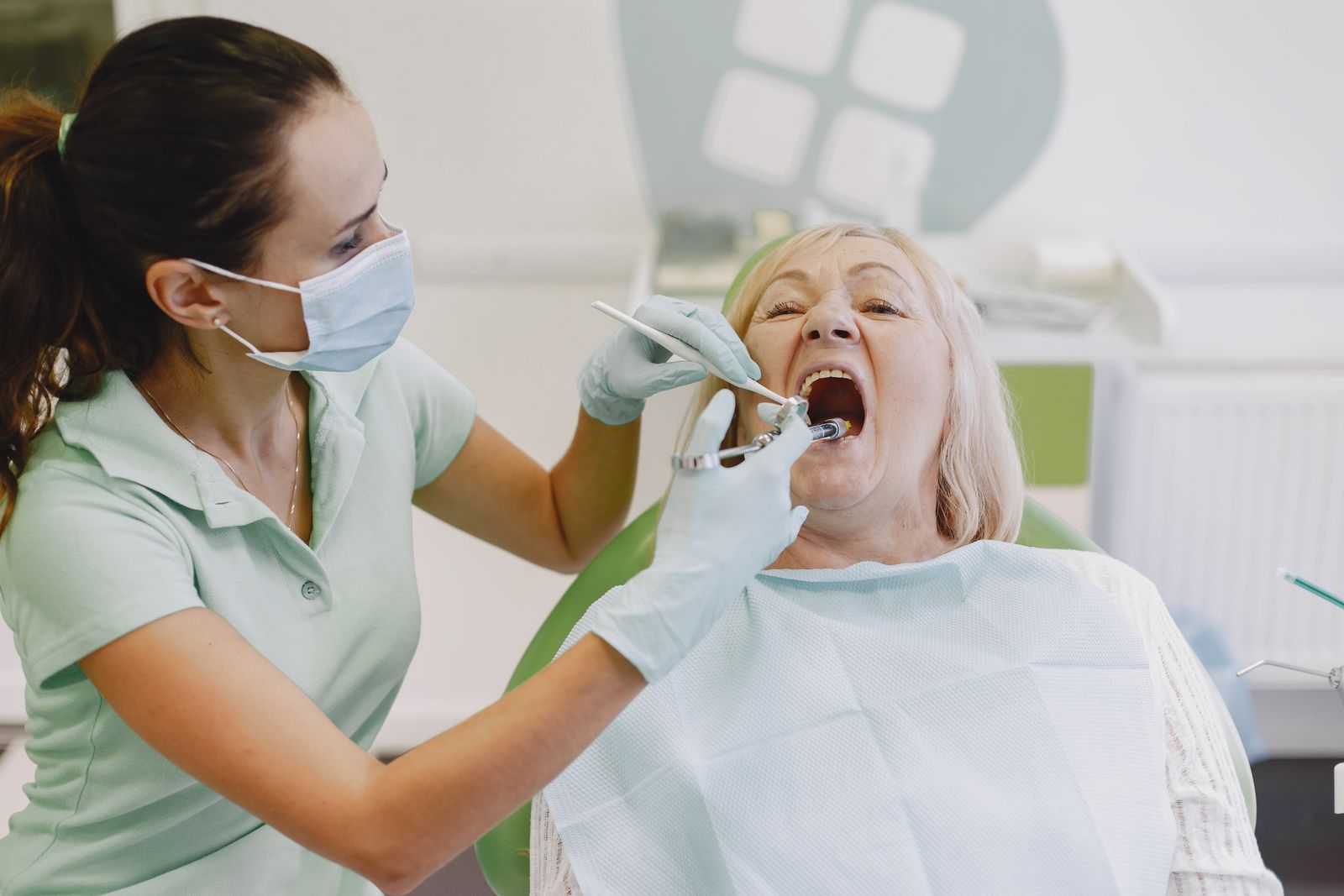 A female dentist examines a senior woman patient in a dental clinic setting