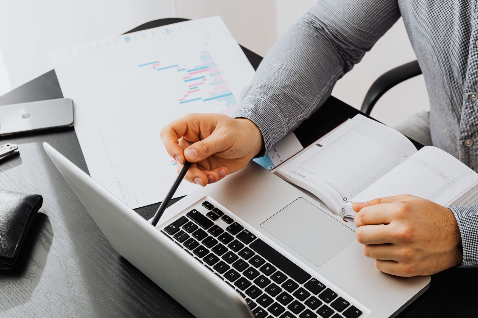 Professional using laptop and reviewing documents at office desk for data analysis