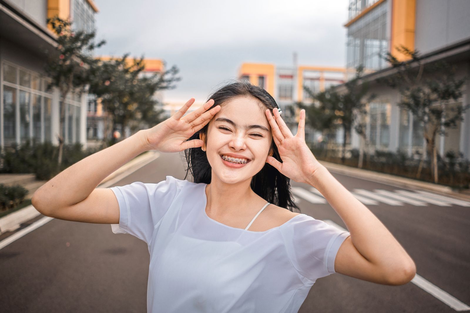 A young woman smiling brightly with braces, enjoying the outdoors