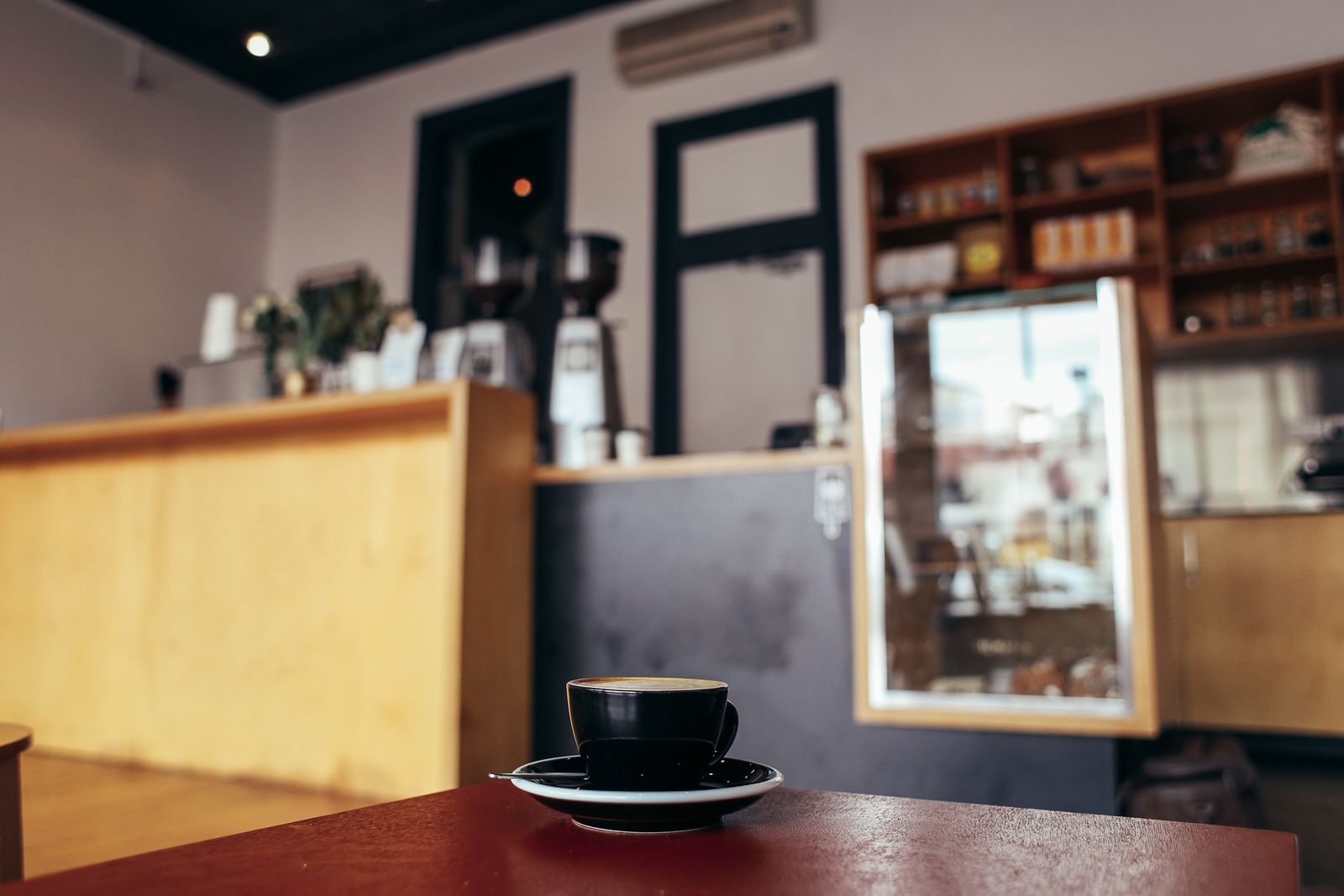 A serene café interior with a focus on a black cup of coffee on the table
