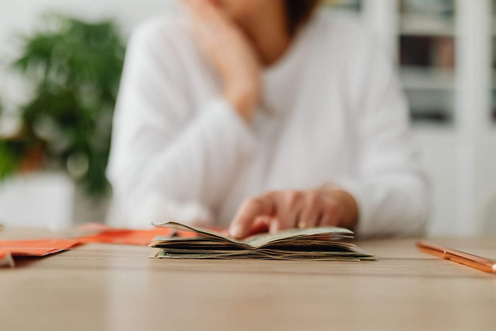 A woman sitting at a desk sorting through cash, focusing on household budgeting