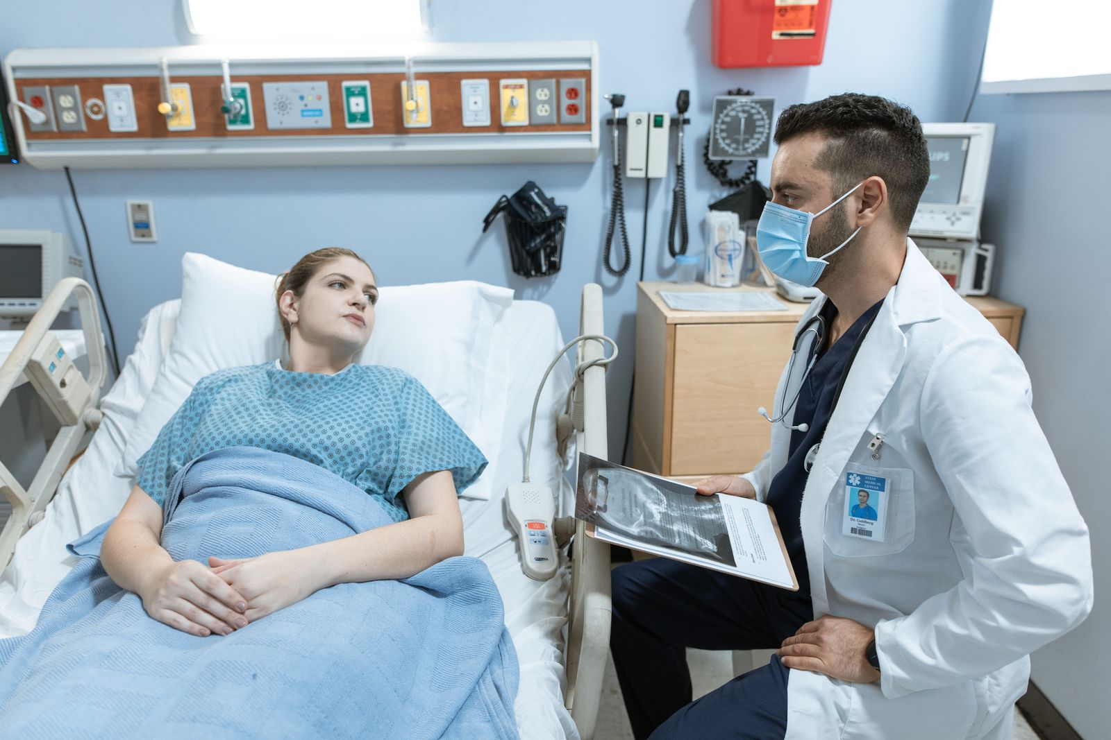 A medical practitioner discusses health details with a patient in a hospital setting