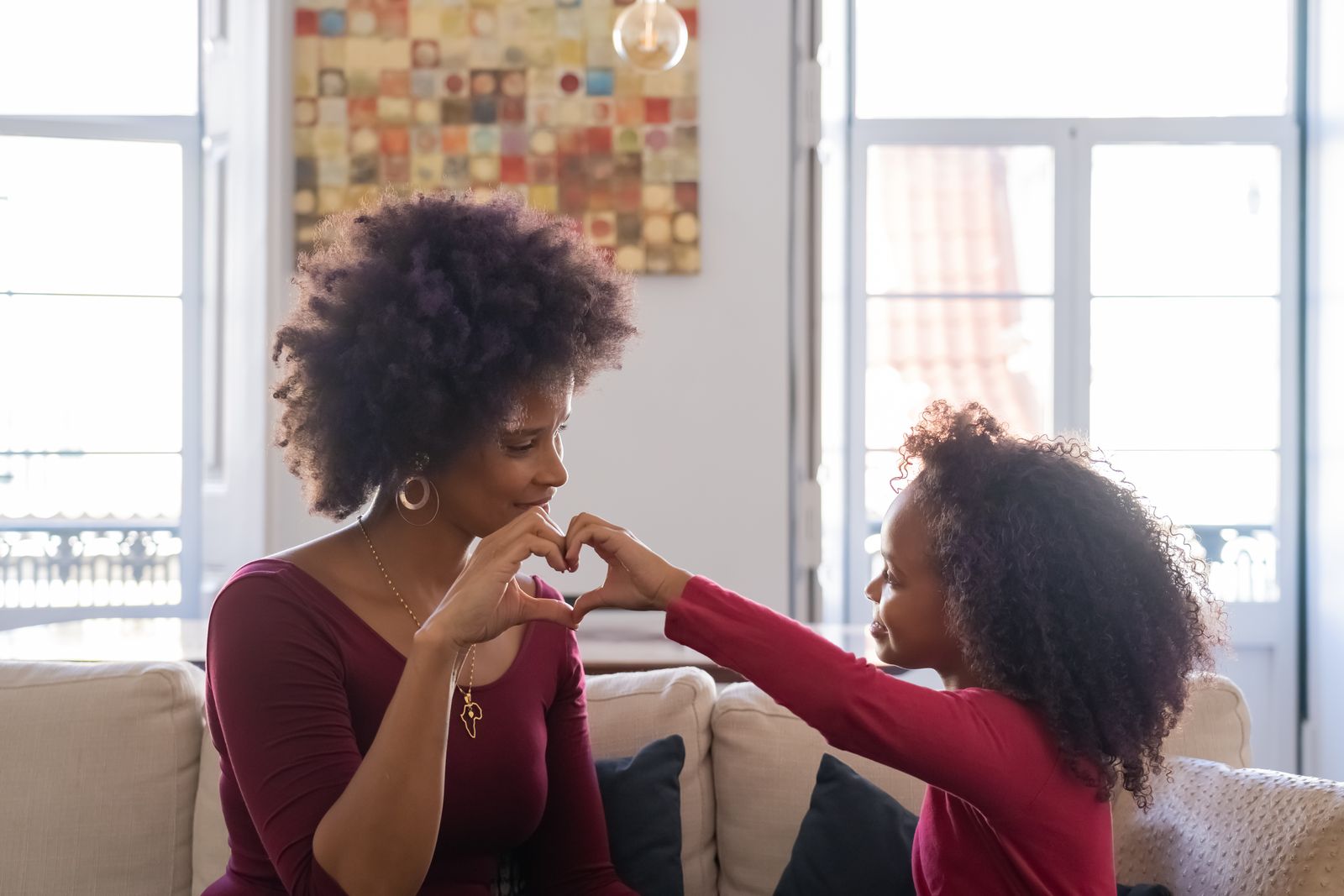 A mother and daughter creating a heart shape with their hands, expressing love and connection