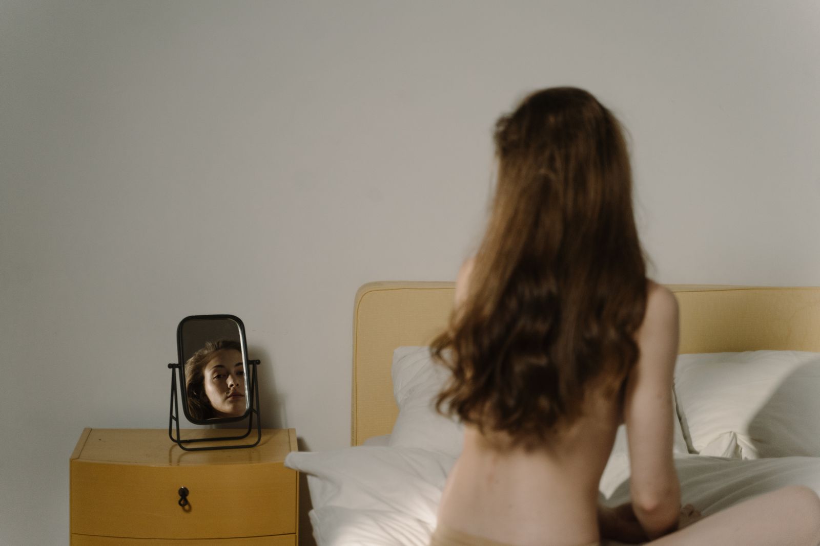 A woman reflects on natural beauty in a bedroom setting with a mirror
