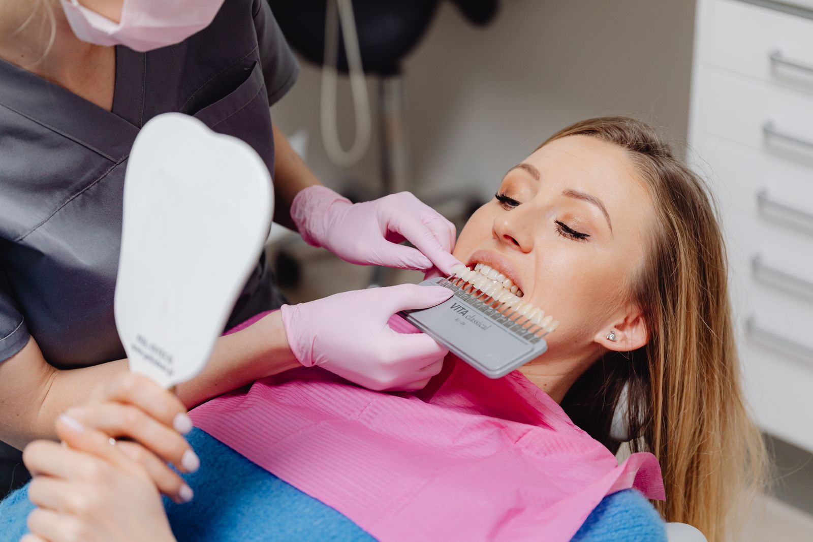 Dentist using a shade guide to match tooth color for a patient in a dental clinic