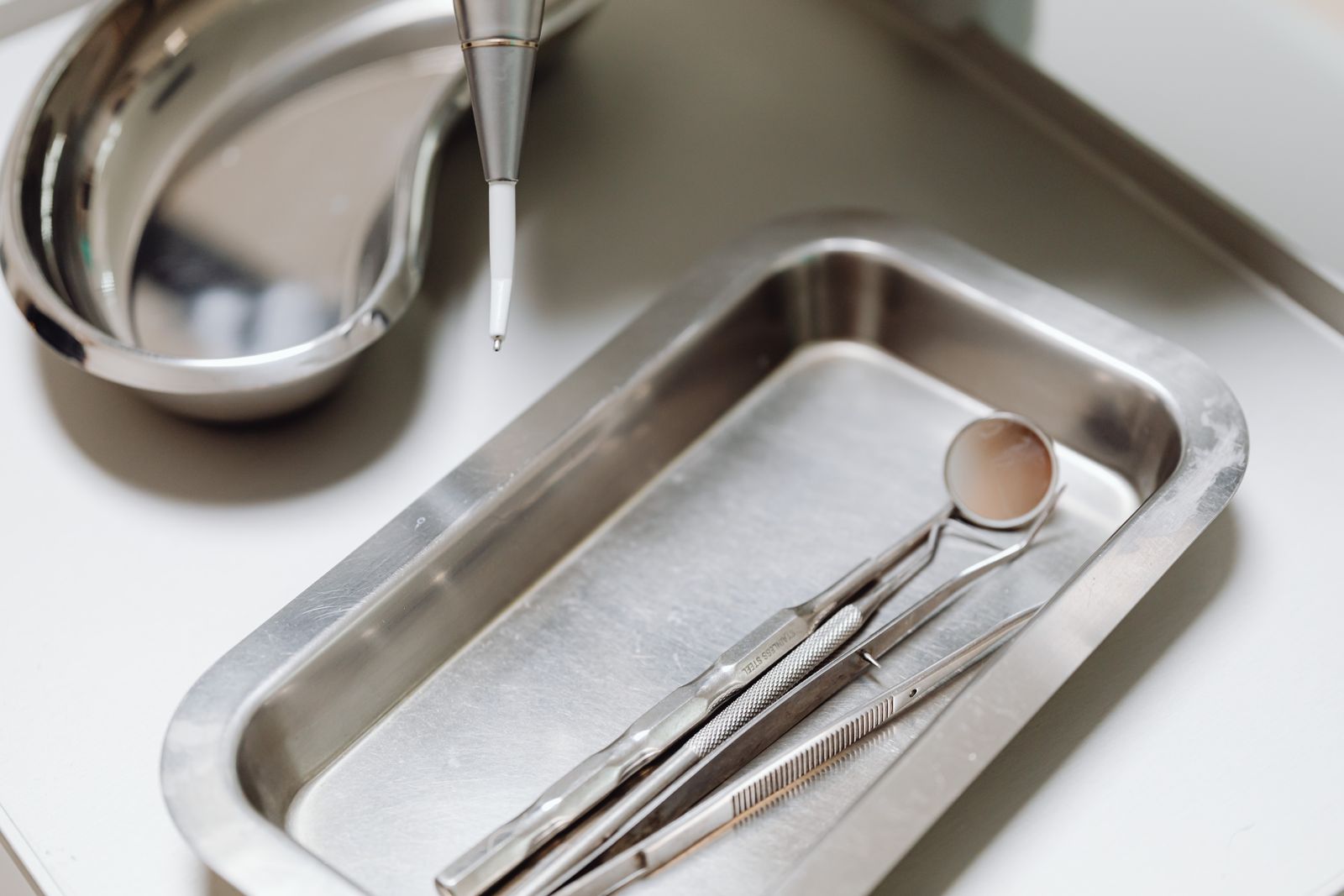 Close-up of dental tools on a clean, sterile metal tray, emphasizing hygiene and precision