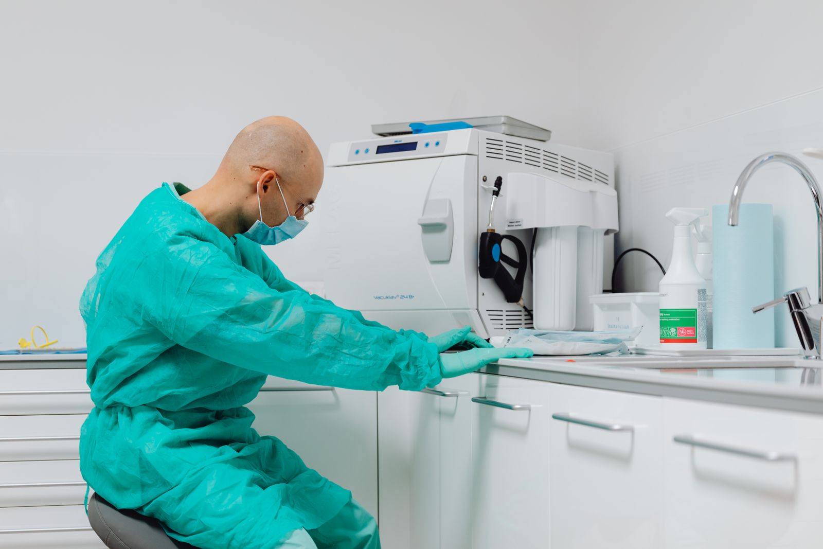 Dentist in sterile gloves and gown at dental office's cleaning area