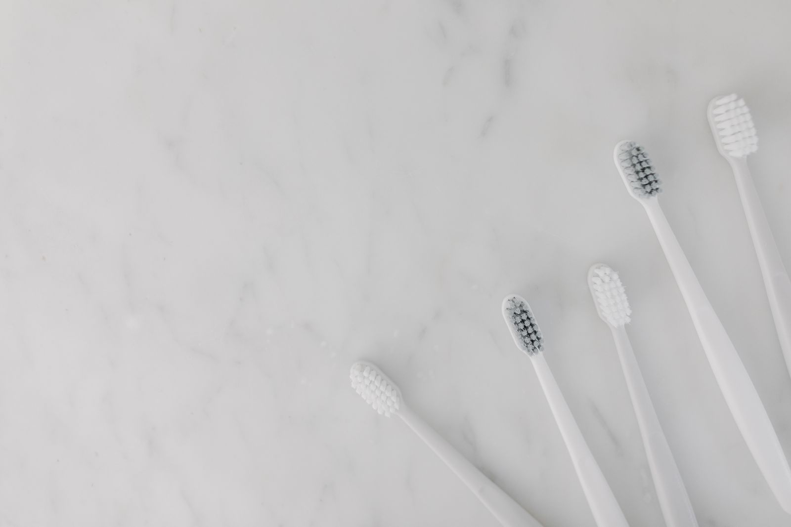Elegant display of white toothbrushes on a marble surface, emphasizing hygiene and simplicity