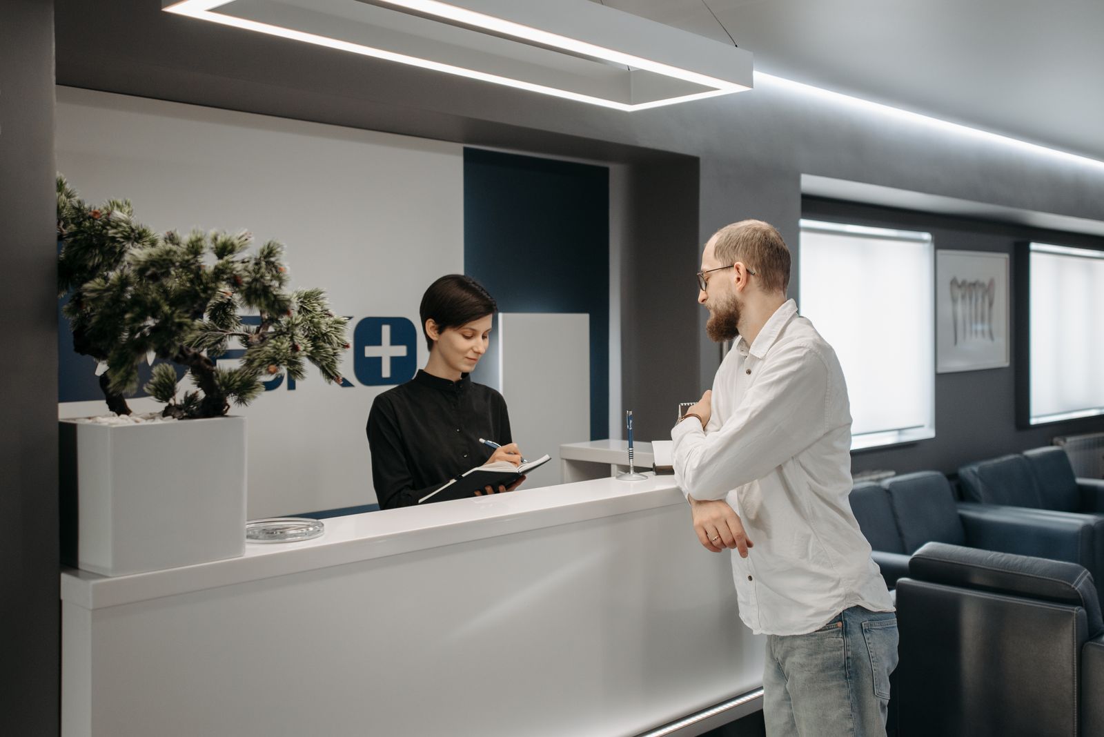 A man consults a receptionist in a modern clinic setting with contemporary design